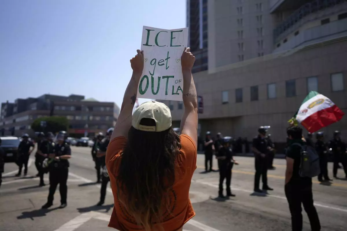 A protester holds a sign up in front of the Metropolitan Detention Center in downtown Los Angeles on Monday, June 9, 2025. (AP Photo/Eric Thayer)