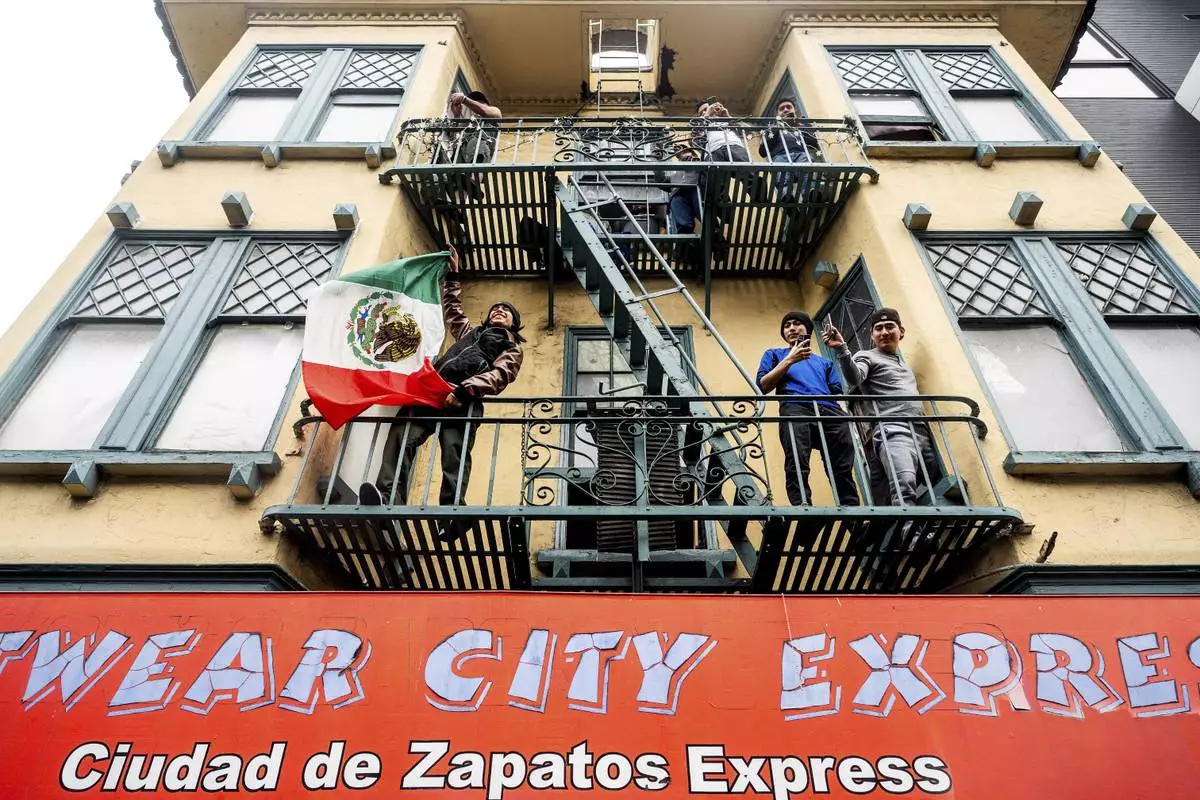A man waves a Mexican flag as protesters against U.S. Immigration & Customs Enforcement raids march through San Francisco's Mission district on Monday, June 9, 2025. (AP Photo/Noah Berger)