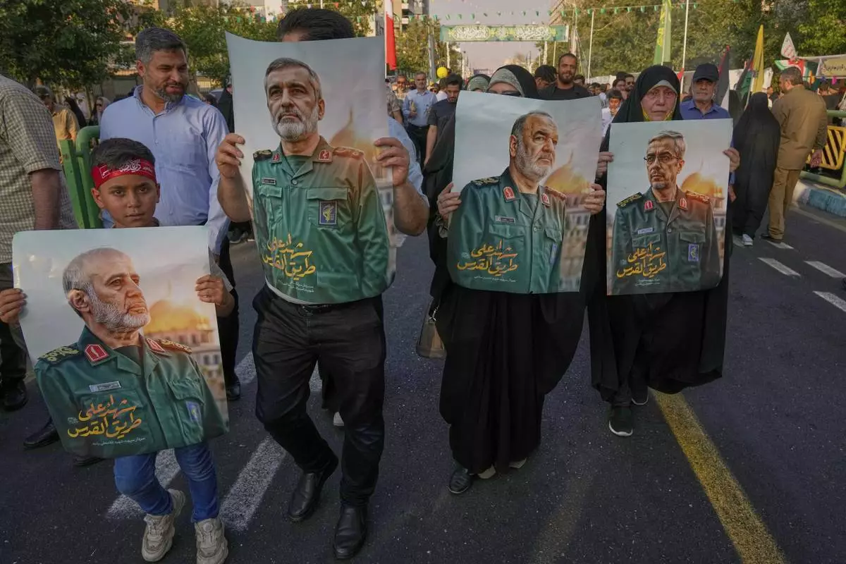 Demonstrators carry posters of top Iranian commanders killed in Friday's Israeli strikes on Tehran, during the Muslim Shiite holiday of Eid al-Ghadir, which commemorates the Prophet Muhammad naming Ali, revered as the first Shiite imam, as his successor, in Tehran, Iran, Saturday, June 14, 2025. (AP Photo/Vahid Salemi)