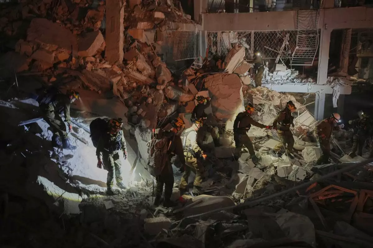 Israeli security forces inspect a destroyed building that was hit by a missile fired from Iran, near Tel Aviv, Israel, early Sunday, June 15, 2025. (AP Photo/Ohad Zwigenberg)