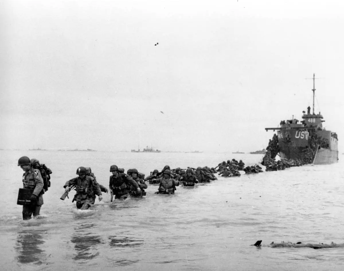 FILE - U.S. reinforcements wade through the surf from a landing craft in the days following D-Day and the Allied invasion of Nazi-occupied France at Normandy in June 1944 during World War II. (Bert Brandt/Pool via AP, File)