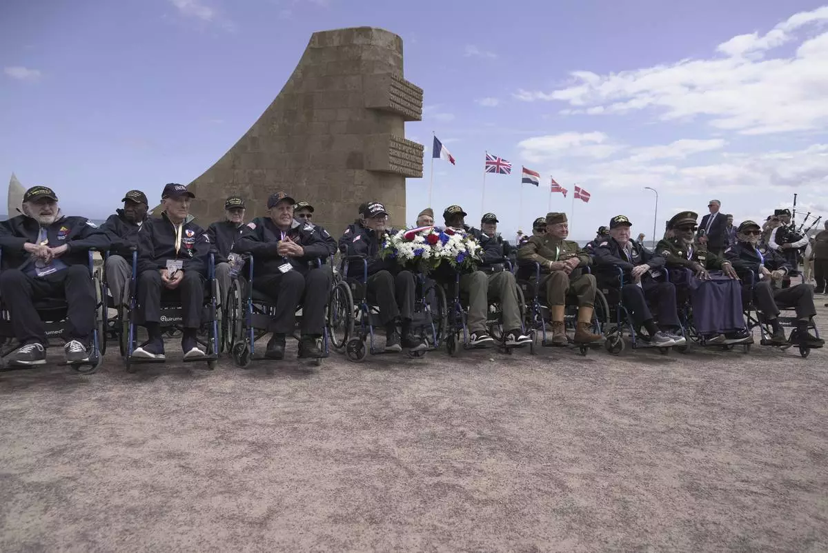 World War II veterans, mostly centenarians, who traveled as a group to France with the non-profit Best Defense Foundation, pose for a photo on Monday, June 2, 2025, at a memorial on Omaha beach, which was one of the D-D-day invasion spots on June 6, 1944. (AP Photo/John Leicester)