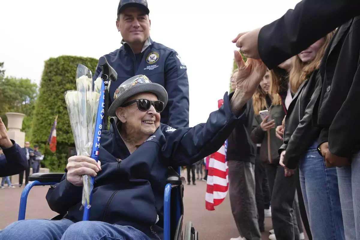 D-Day veteran Jake Larson, a 102-year-old who is also a star on TikTok, with 1.2 million followers, greets schoolchildren during a visit Monday, June 2, 2025 in Colleville-sur-Mer, to the Normandy American Cemetery that is the final resting place for nearly 9,400 American war dead and which overlooks Omaha beach, one of the D-D-day invasion zones on June 6, 1944. (AP Photo/John Leicester)