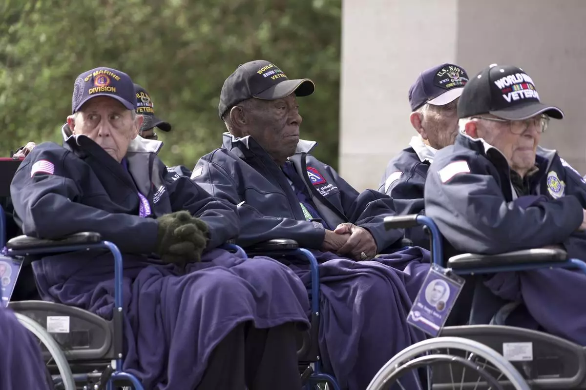 Calvin Shiner, center, a 102-year-old who was drafted in 1943 into the then-racially segregated U.S. military to serve in an all-Black construction unit, and other veterans of World War II attend a commemoration on Monday, June 2, 2025 in Colleville-sur-Mer, at the Normandy American Cemetery that is the final resting place for nearly 9,400 American war dead and which overlooks Omaha beach, one of the D-D-day invasion zones on June 6, 1944. (AP Photo/John Leicester)