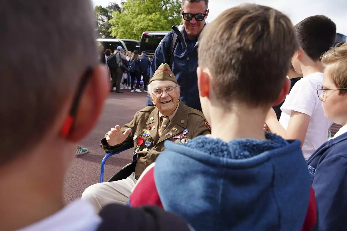 World War II veteran Wilbur "Jack" Myers, a 101-year-old who fought in the U.S. Army's 692nd Tank Destroyer Battalion, greets schoolchildren during a visit on Monday, June 2, 2025 in Colleville-sur-Mer, to the Normandy American Cemetery that is the final resting place for nearly 9,400 American war dead and which overlooks Omaha beach, one of the D-D-day invasion zones on June 6, 1944. (AP Photo/John Leicester)