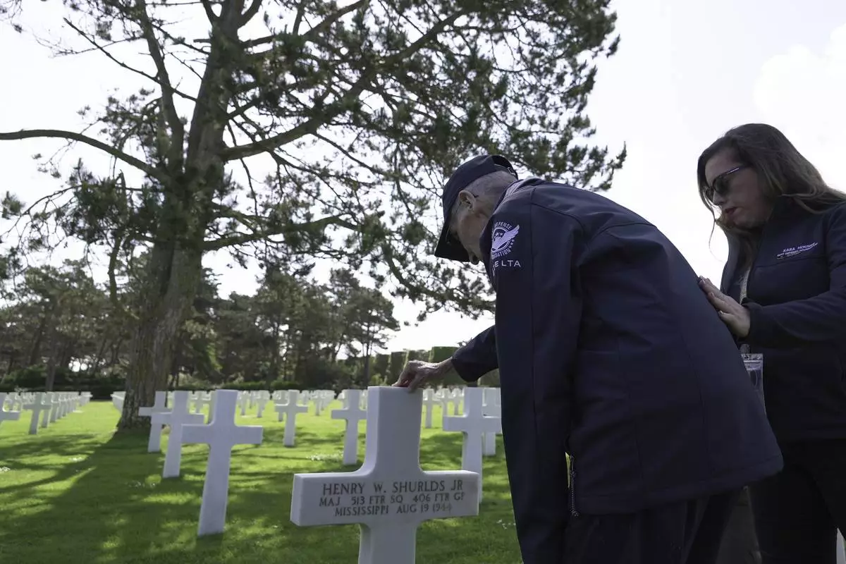 Wally King, a 101-year-old former U.S. fighter pilot who flew 75 combat missions in World War II, and his granddaughter Kara Houser pay their respects Monday, June 2, 2025 in Colleville-sur-Mer, at the Normandy American Cemetery grave of Henry Shurlds Jr., who flew P-47 "Thunderbolt" fighters like King and was shot down and killed on Aug. 19, 1944, above the town of Verneuil-sur-Seine, northwest of Paris. (AP Photo/John Leicester).