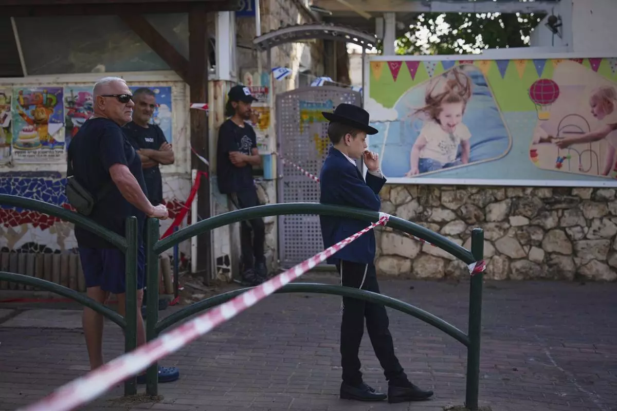 Residents look at the site where an Iranian missile struck in, Haifa, Israel, Monday, June 16, 2025. (AP Photo/Ariel Schalit)