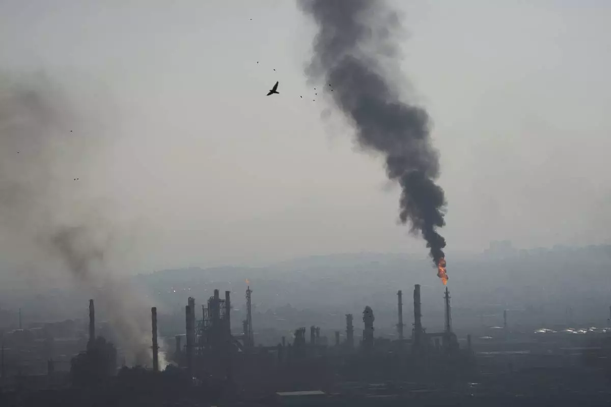 Smoke billows after an Iranian missile struck an oil refinery in Haifa, northern Israel, early Monday, June 16, 2025. (AP Photo/Ariel Schalit)