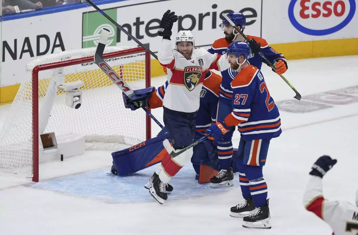 Florida Panthers' Sam Bennett (9) celebrates Brad Marchand's goal against Edmonton Oilers goalie Stuart Skinner as Brett Kulak (27) and Jake Walman (96) look on during the first period in Game 1 of the NHL hockey Stanley Cup final series in Edmonton, Alberta, Wednesday, June 4, 2025. (Darryl Dyck/The Canadian Press via AP)