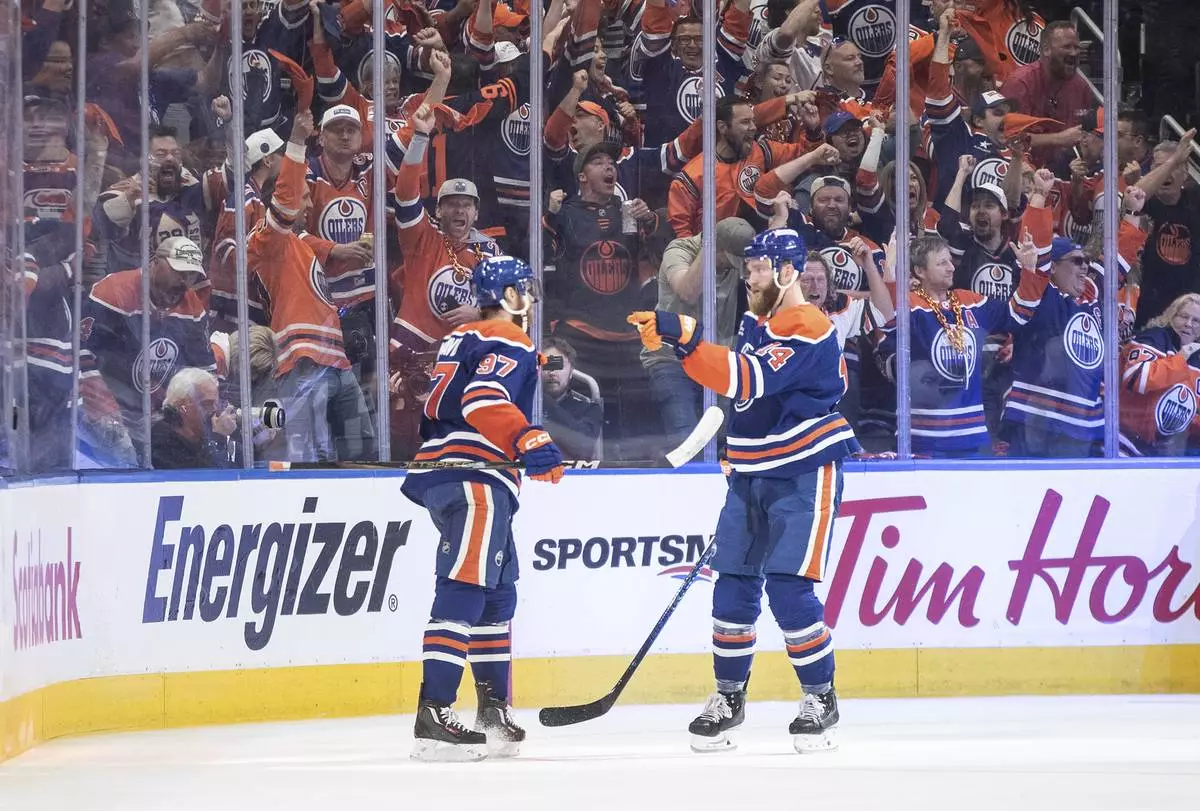 Edmonton Oilers' Connor McDavid (97) and Mattias Ekholm (14) celebrate a goal against the Florida Panthers during the third period in Game 1 of the NHL hockey Stanley Cup final series in Edmonton, Alberta, Wednesday, June 4, 2025. (Jason Franson/The Canadian Press via AP)