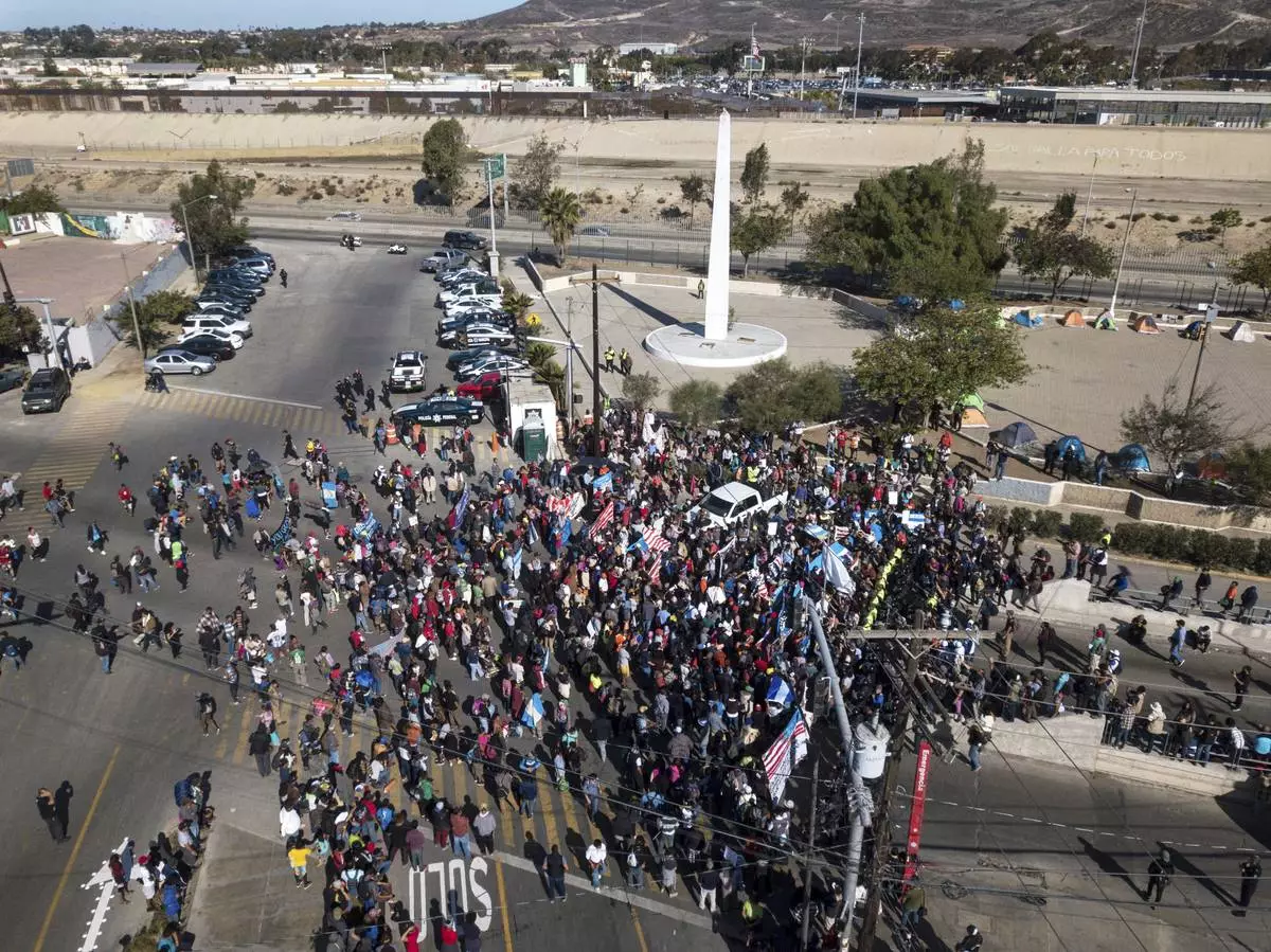 FILE - A group of migrants gather at the Chaparral border crossing in Tijuana, Mexico, Nov. 25, 2018, as the mayor of Tijuana declares a humanitarian crisis in his border city and says that he has asked the United Nations for aid to deal with the approximately 5,000 Central American migrants who have arrived in the city. (AP Photo/Rodrigo Abd, File)