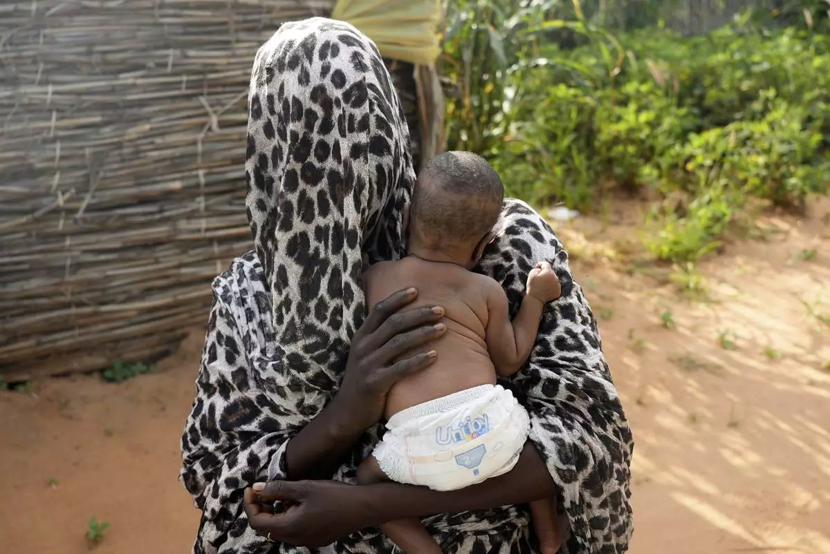 FILE - A woman who fled war in Sudan and requested anonymity because she feared retribution after reporting sexual exploitation, holds her baby in a refugee camp in Adre, Chad, Oct. 5, 2024. (AP Photo/Sam Mednick, File)