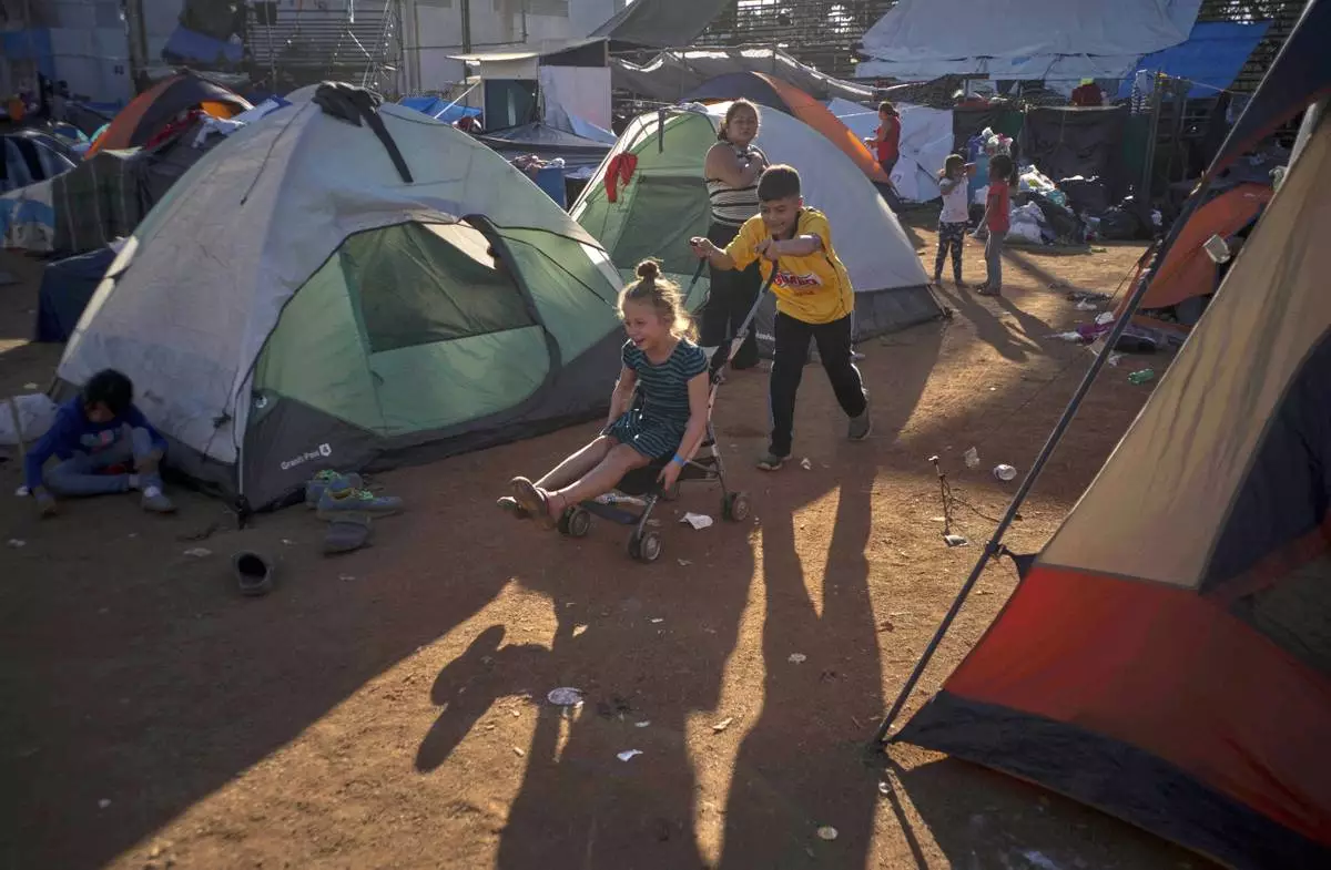 FILE - Children play at the Benito Juarez Sports Center that's serving as a temporary shelter in Tijuana, Mexico, Nov. 26, 2018, afternoon the mayor of Tijuana declared a humanitarian crisis in his border city and says that he has asked the United Nations for aid to deal with thousands of Central American migrants who have arrived in the city. (AP Photo/Ramon Espinosa, File)
