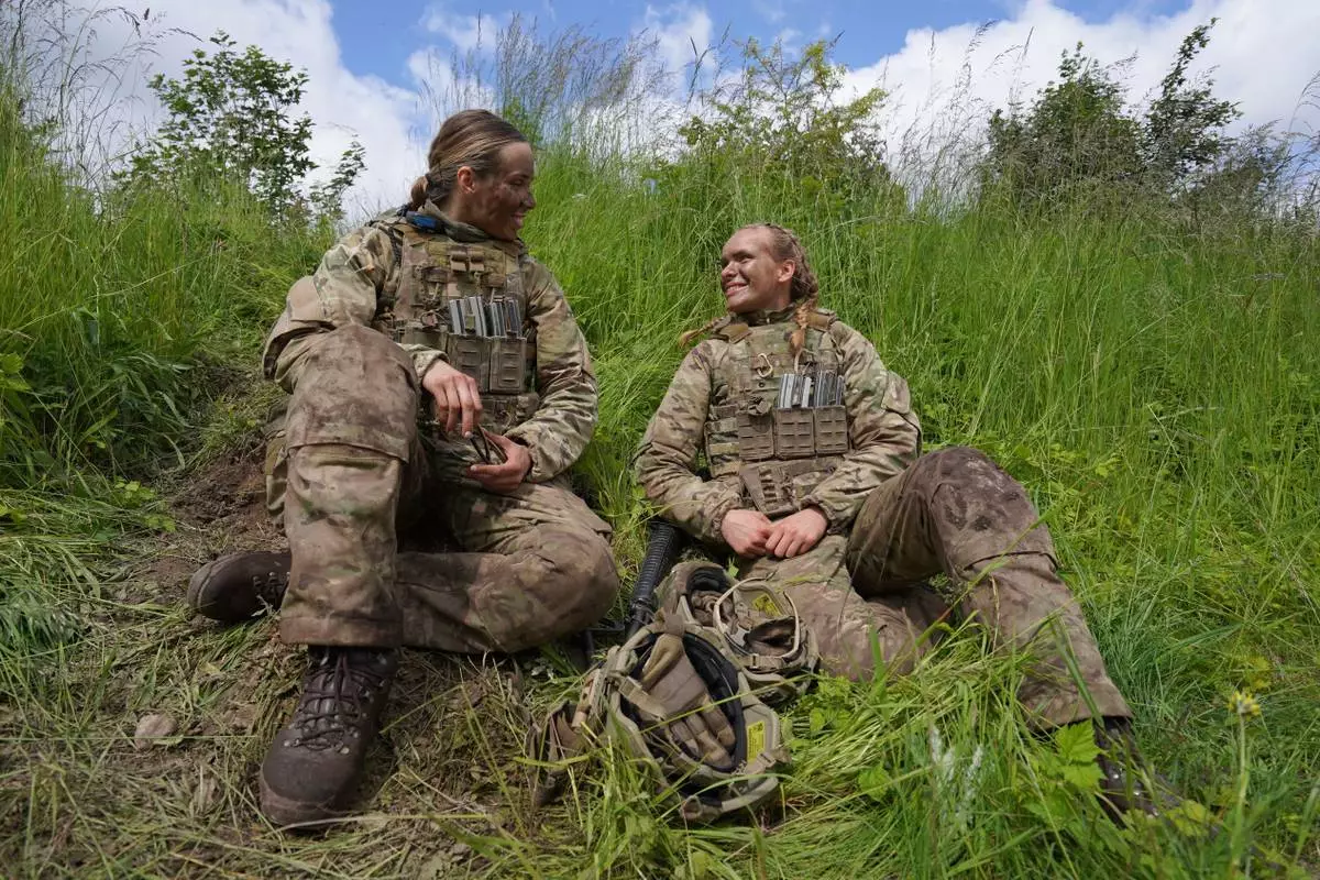 CORRECTS THE NAME OF PERSON'S ROLE - 20-year-old Katrine, right, speaks with another female servicemember during final exercises at a training area close to Royal Danish Army’s barracks in Hovelte, 25 kilometres north of Copenhagen, Denmark, Wednesday, June 11, 2025. (AP Photo/James Brooks)