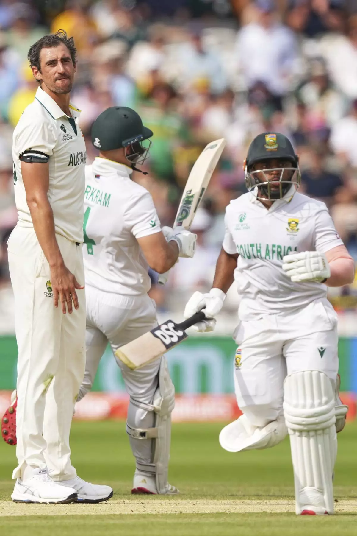 Australia's Mitchell Starc, left, reacts as South Africa's captain Temba Bavuma, right, and batting partner Aiden Markram run between the wickets to score on day three of the World Test Championship final between South Africa and Australia at Lord's cricket ground in London, Friday, June 13, 2025. (AP Photo/Kirsty Wigglesworth)