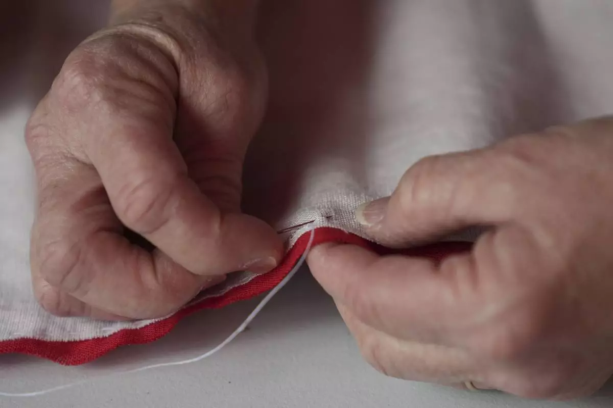 Cornelia Bridges demonstrates how a flag is stitched together at the Betsy Ross House in Philadelphia, Monday, June 9, 2025. (AP Photo/Matt Rourke)