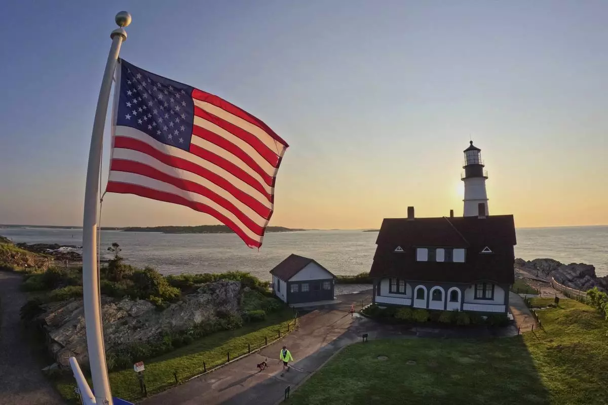 An American flag at Portland Head Light catches the light at sunrise, Wednesday, June 11, 2025, in Cape Elizabeth, Maine. (AP Photo/Robert F. Bukaty)