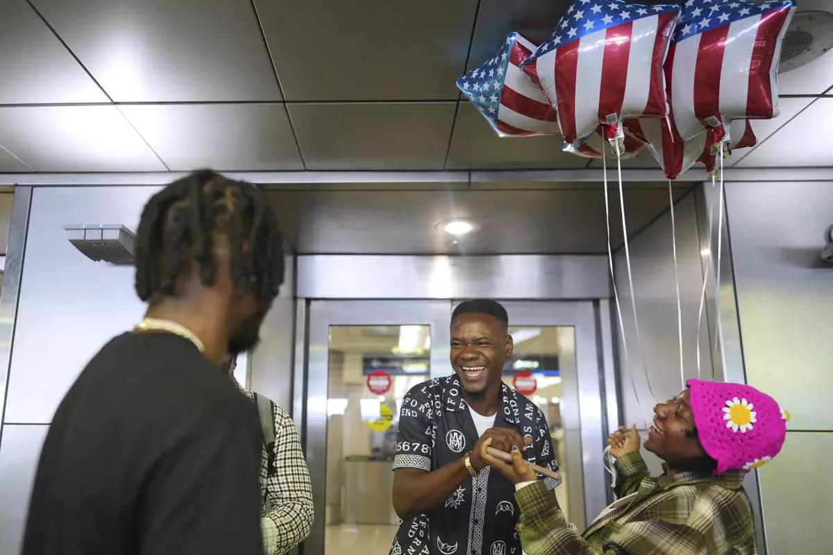 Key Felix, center, of Haiti, is greeted by his sister, carrying American flag balloons, as he arrives in Miami for his first visit to the U.S., at Miami International Airport, Monday, June 9, 2025. (AP Photo/Rebecca Blackwell)