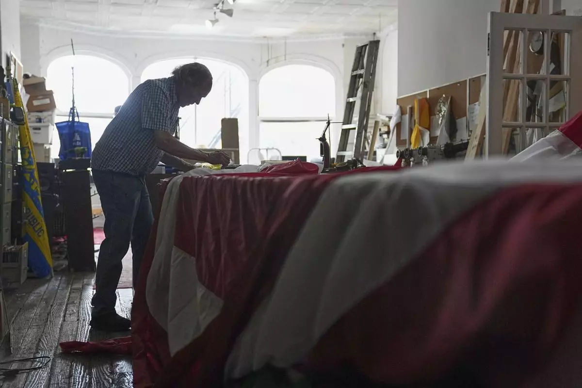 Tim O'Connor works on a large United States flag at Humphrys Flag Company that will be draped outside their building for Flag Day, in Philadelphia, Tuesday, June 10, 2025. (AP Photo/Matt Rourke)