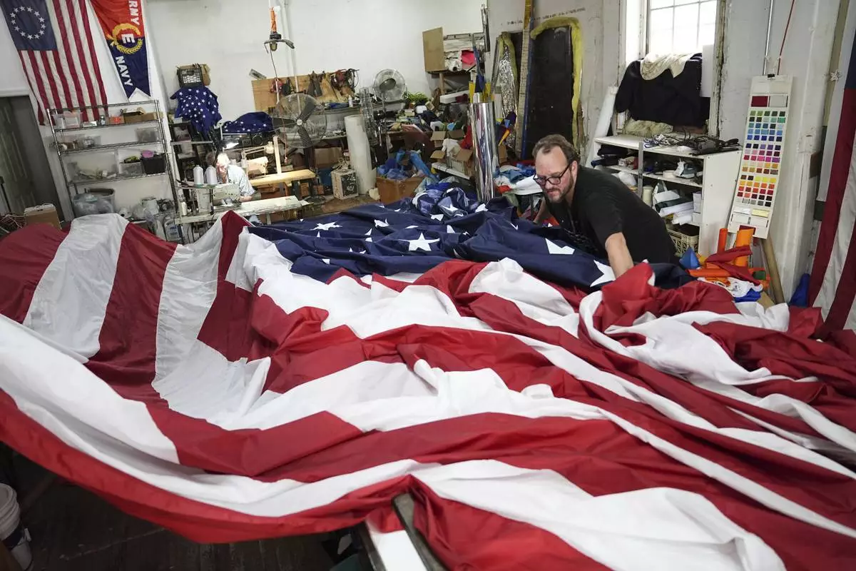Tim O'Connor, back left, and his son Matthew O'Connor, work on a large United States flag at Humphrys Flag Company that will be draped outside their building for Flag Day, in Philadelphia, Tuesday, June 10, 2025. (AP Photo/Matt Rourke)