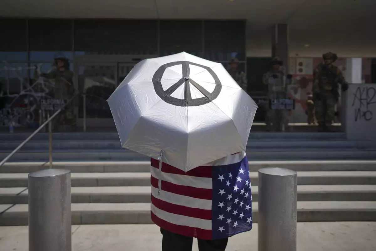 A protester stands in front of a line of law enforcement personnel at a Federal Building on Monday, June 9, 2025, in downtown Los Angeles. (AP Photo/Eric Thayer)