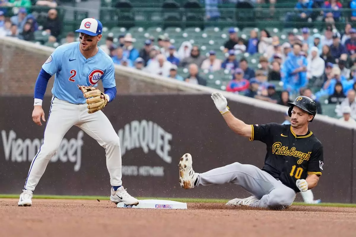 Pittsburgh Pirates Bryan Reynolds (10) slides safely into second base with a double as Chicago Cubs second base Nico Hoerner (2) waits for a throw during the first inning of a baseball game Friday, June 13, 2025, in Chicago. (AP Photo/David Banks)