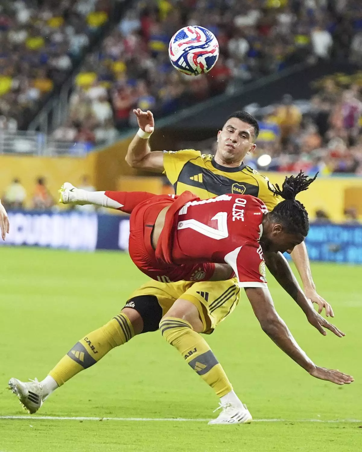 Bayern Munich's Michael Olise, front, and Boca Juniors' Rodrigo Battaglia, top, collide as they compete for the ball during the Club World Cup Group C soccer match between Bayern Munich and Boca Juniors in Miami Gardens, Fla., Friday, June 20, 2025. (AP Photo/Lynne Sladky)
