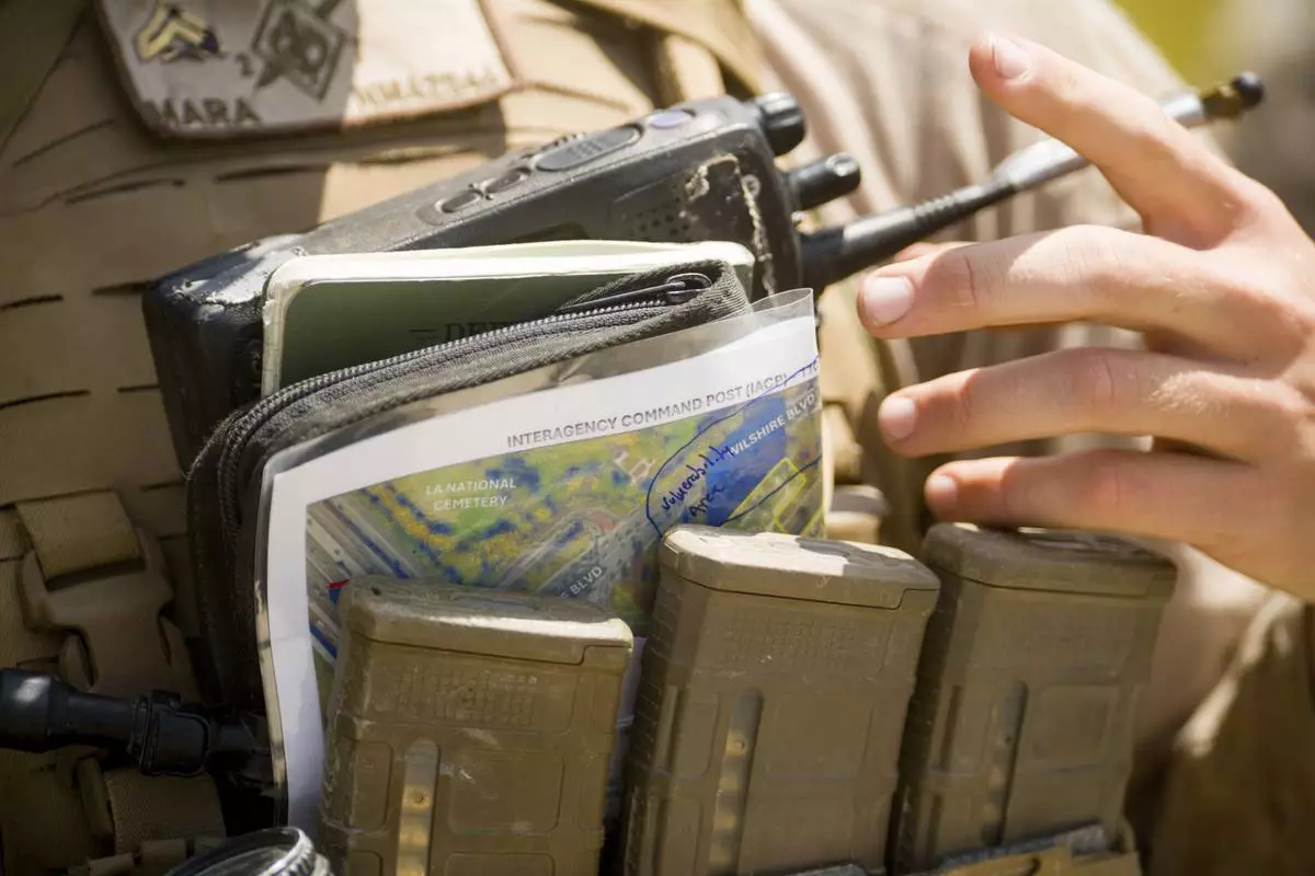 A U.S Marine adjusts their radio and outside of a federal building Friday, June 13, 2025, in Los Angeles (AP Photo/Noah Berger)