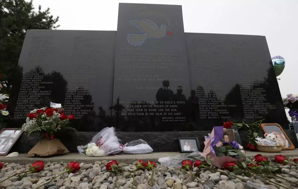 FILE - Flowers and pictures are shown at the memorial in Romulus, Mich., to mark the 25th anniversary of the crash of Northwest Airlines Flight 255 near Detroit Metropolitan Airport, Aug. 16, 2012. The MD-80 aircraft crashed in the Detroit suburb of Romulus, killing all 154 people aboard, except for a 4-year-old girl. Two people also died on the ground. (AP Photo/Paul Sancya, File)