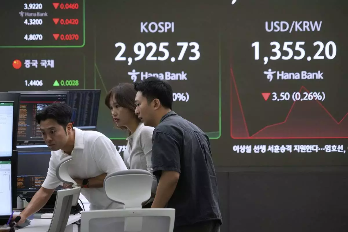 Currency traders watch monitors near a screen showing the Korea Composite Stock Price Index (KOSPI) and the foreign exchange rate between U.S. dollar and South Korean won, right, at the foreign exchange dealing room of the KEB Hana Bank headquarters in Seoul, South Korea, Friday, June 13, 2025. (AP Photo/Ahn Young-joon)