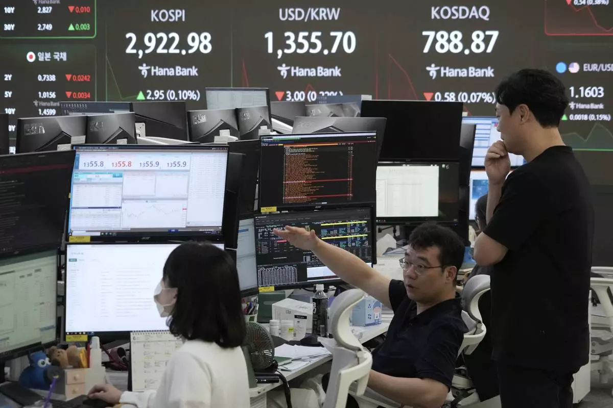 Currency traders work near a screen showing the Korea Composite Stock Price Index (KOSPI), top left, and the foreign exchange rate between U.S. dollar and South Korean won, top center, at the foreign exchange dealing room of the KEB Hana Bank headquarters in Seoul, South Korea, Friday, June 13, 2025. (AP Photo/Ahn Young-joon)