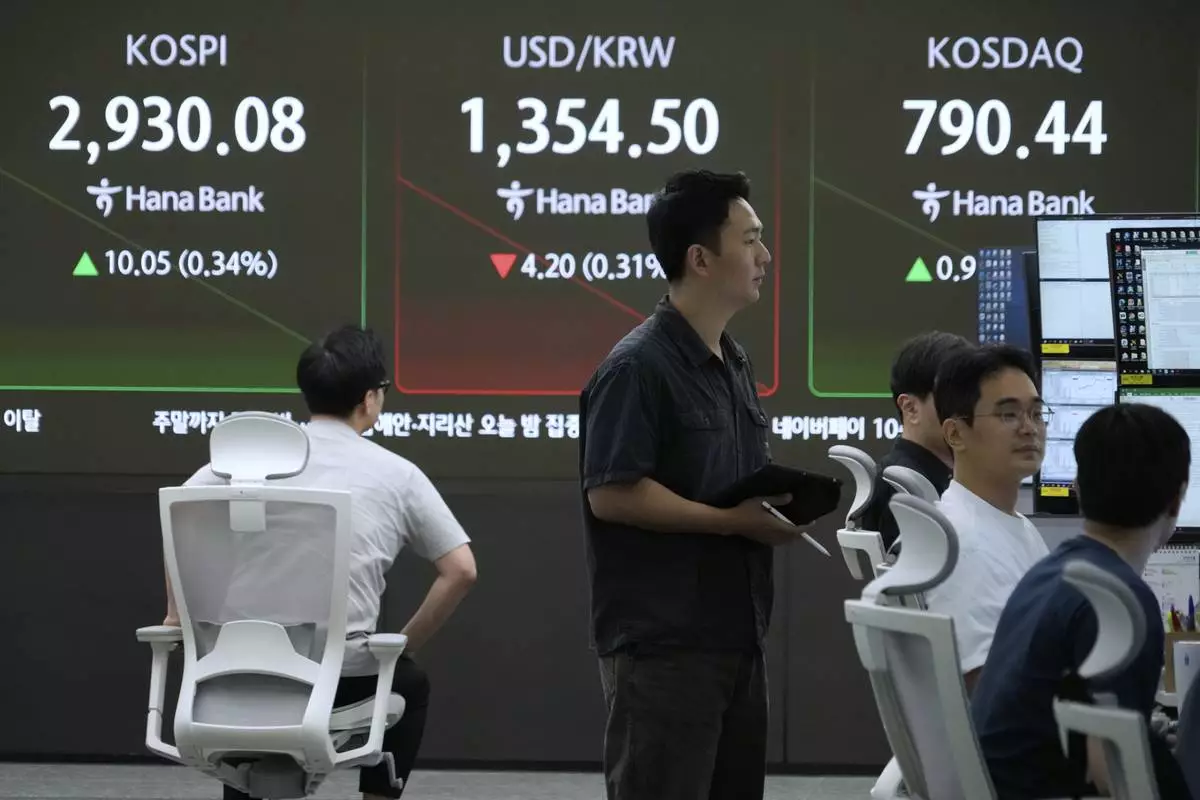 Currency traders work near a screen showing the Korea Composite Stock Price Index (KOSPI), top left, and the foreign exchange rate between U.S. dollar and South Korean won, top center, at the foreign exchange dealing room of the KEB Hana Bank headquarters in Seoul, South Korea, Friday, June 13, 2025. (AP Photo/Ahn Young-joon)
