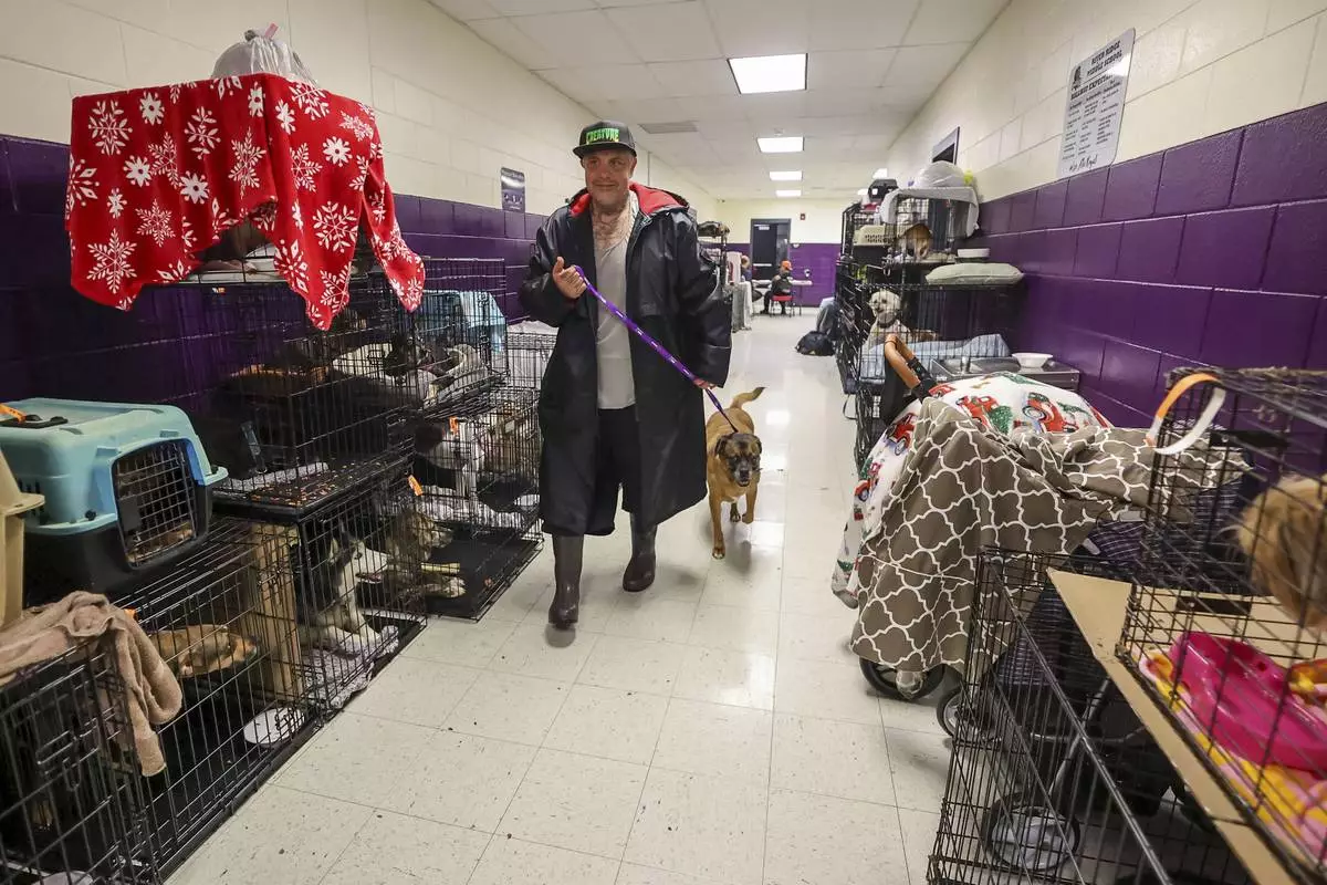 FILE - Logan Smith walks his dog, Zak, past some of the 283 registered pets in the evacuation shelter at River Ridge Middle/High School in preparation for Hurricane Milton on Wednesday, Oct. 9, 2024, in New Port Richey, Fla. (AP Photo/Mike Carlson, File)