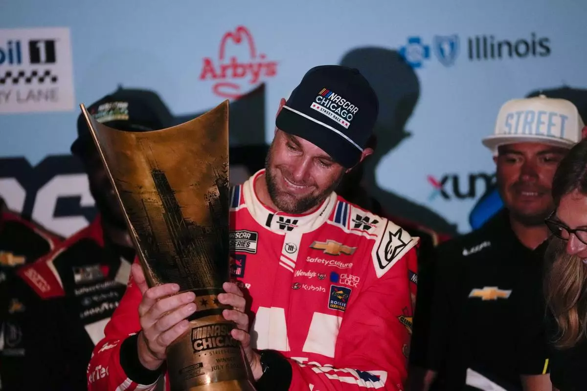 Shane van Gisbergen, center, holds the trophy after winning a NASCAR Cup Series auto race at the Grant Park 165, Sunday, July 6, 2025, in Chicago. (AP Photo/Erin Hooley)