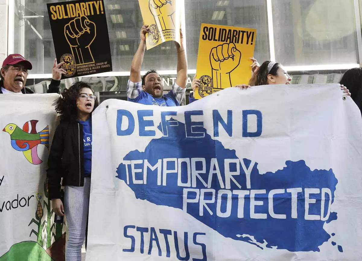 FILE - Supporters of temporary protected status immigrants hold signs and cheer at a rally before a conference announcing a lawsuit against the Trump administration over its decision to end a program letting immigrants live and work legally in the United States outside of a federal courthouse in San Francisco, March 12, 2018. (AP Photo/Jeff Chiu, File)