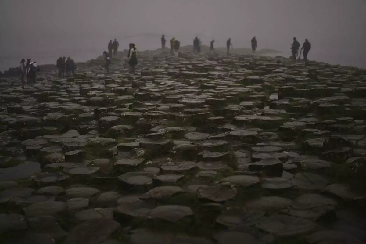 Tourists visit the Giant's Causeway, near Bushmills, County Antrim, Northern Ireland, Monday, July 21, 2025. (AP Photo/Francisco Seco)