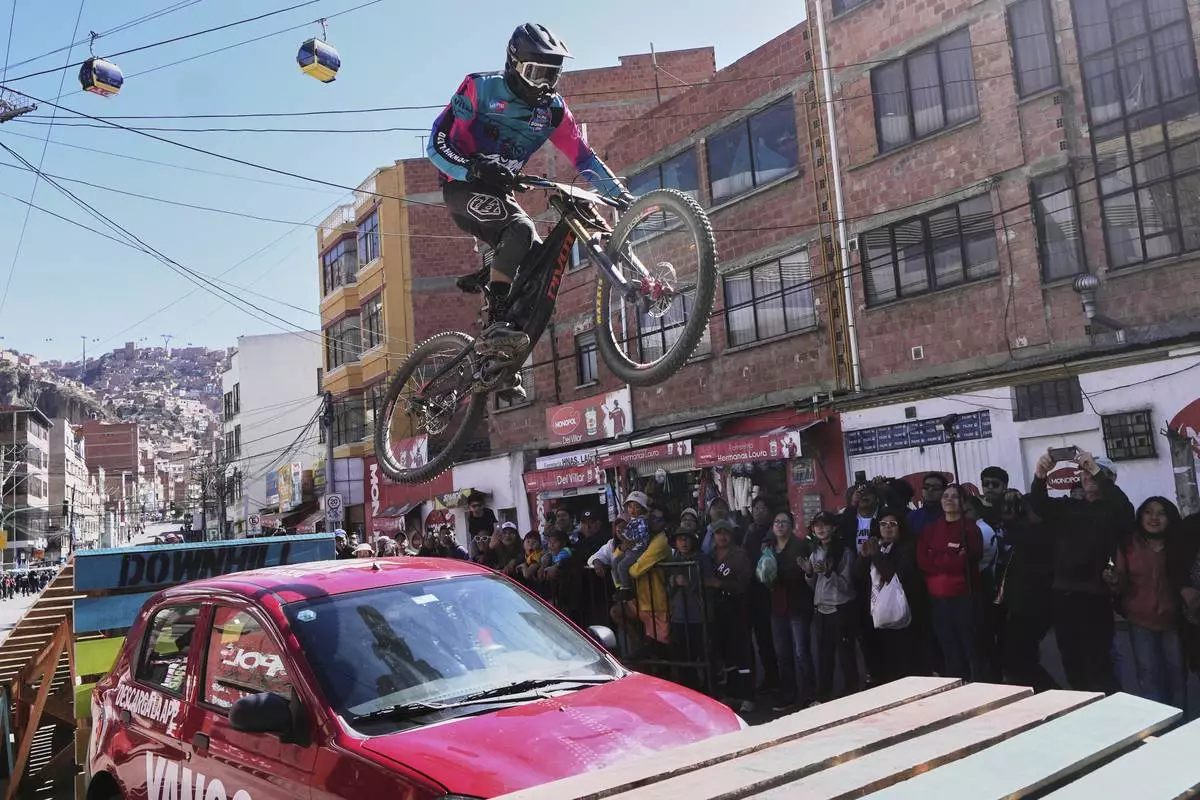 A competitor rides over a car during the Challenge Downhill mountain bike race in La Paz, Bolivia, Sunday, July 6, 2025. (AP Photo/Juan Karita)
