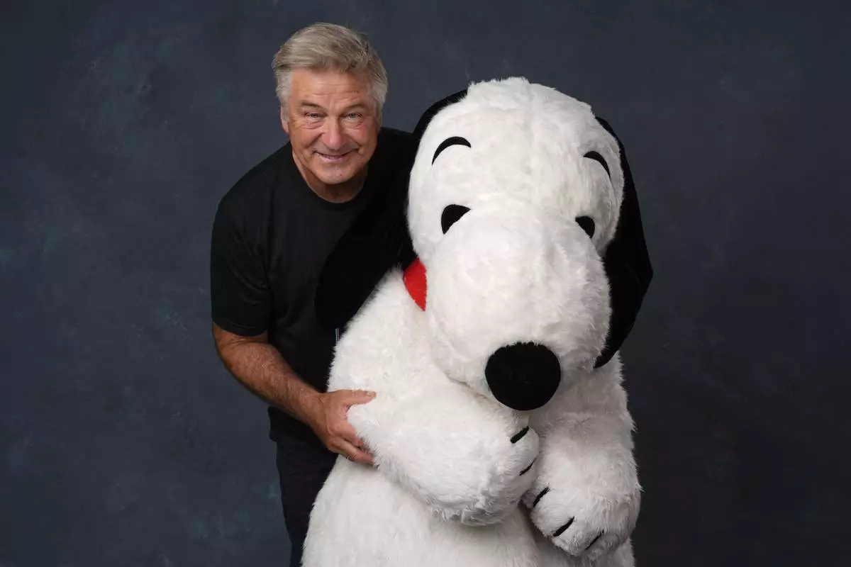 Alec Baldwin, left, and a person dressed as the character Snoopy from "Peanuts" poses for a portrait to promote the 75th anniversary of "Peanuts" during Comic-Con International on Thursday, July 24, 2025, in San Diego. (AP Photo/Chris Pizzello)