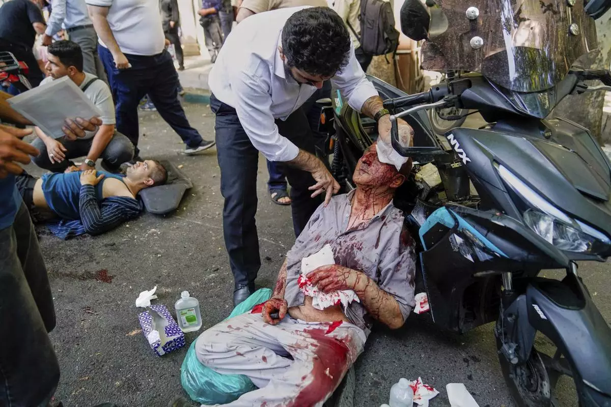An injured man is assisted in the street after an explosion in downtown Tehran, following an Israeli airstrike, Sunday, June 15, 2025. (AP Photo/Amir Kholousi/ISNA)