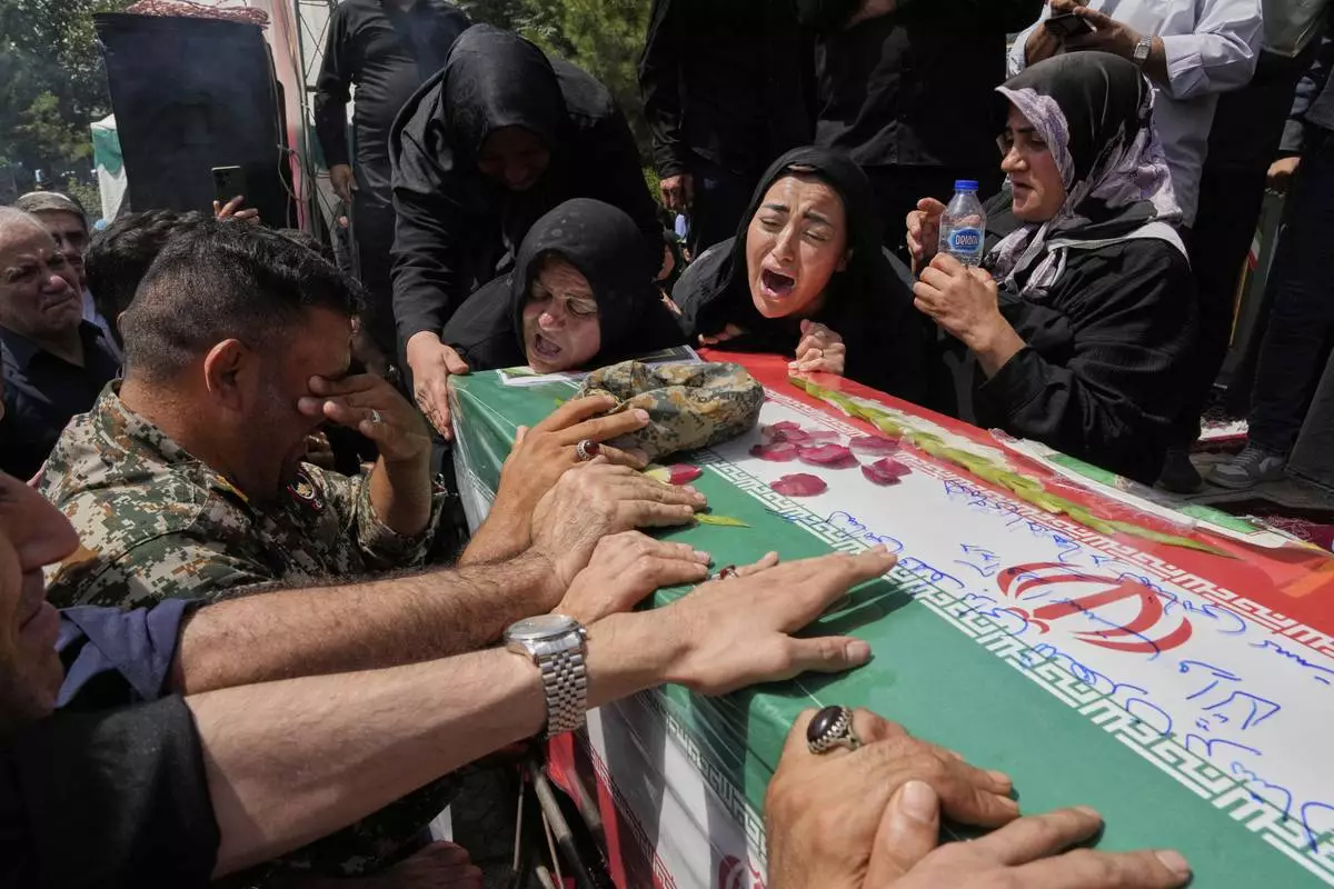 Relatives mourn over the flag-draped coffin of Mahan Setareh, a member of the paramilitary Basij force who was killed in Israeli attacks, during his funeral ceremony in Tehran, Iran, Thursday, June 26, 2025. (AP Photo/Vahid Salemi)