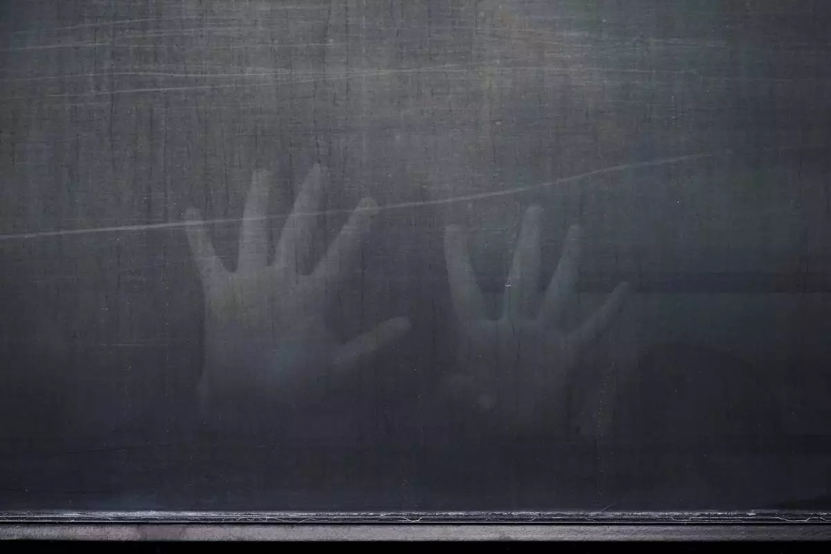 A woman from Peru signals through the barred and tinted windows of a bus after she was detained following an appearance at immigration court, Monday, June 23, 2025, in San Antonio. (AP Photo/Eric Gay)