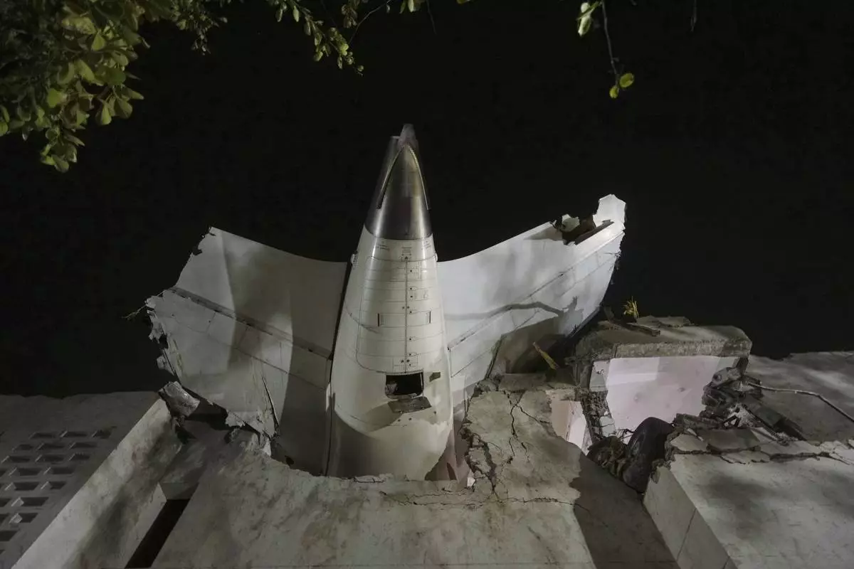 The tail of the airplane is seen stuck in a building at the site of an airplane that crashed in India's northwestern city of Ahmedabad in Gujarat state, Thursday, June 12, 2025. (AP Photo/Ajit Solanki)