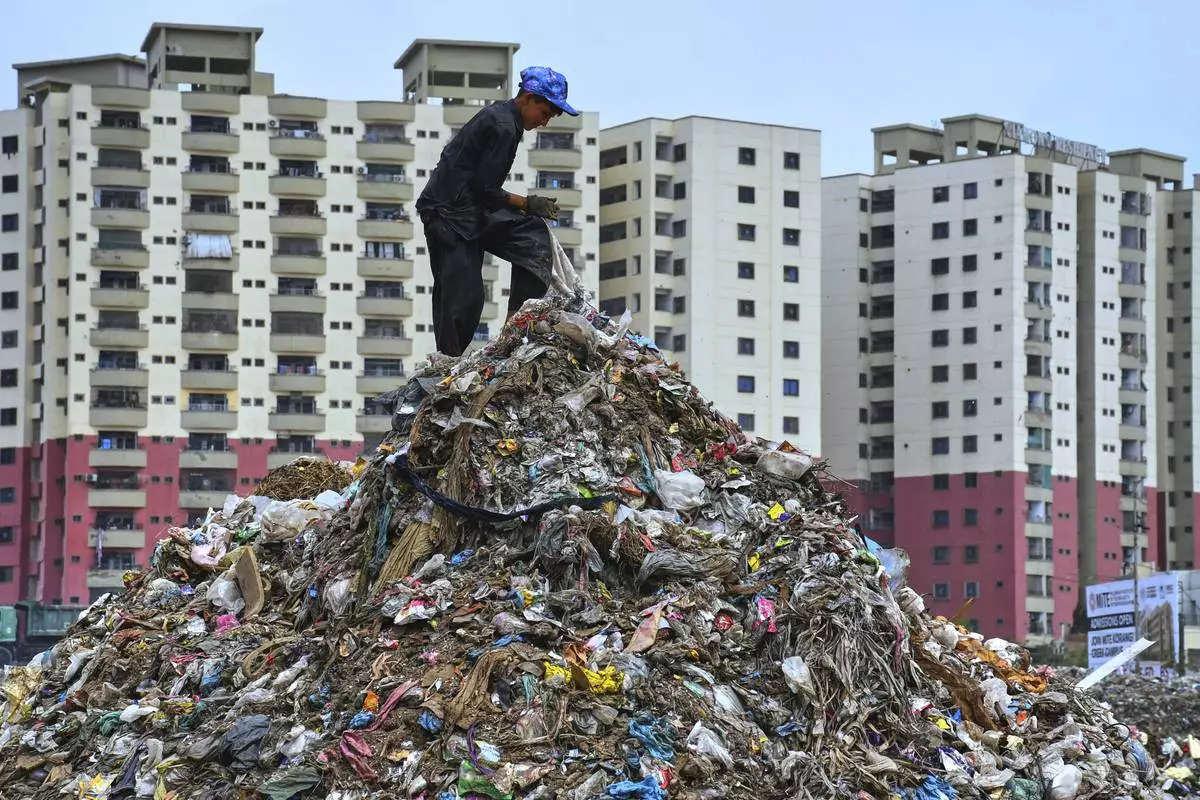 A boy searches for recyclable items from a pile of garbage at a dump site on World Environment Day, in Karachi, Pakistan, Thursday, June 5, 2025. (AP Photo/Ali Raza)