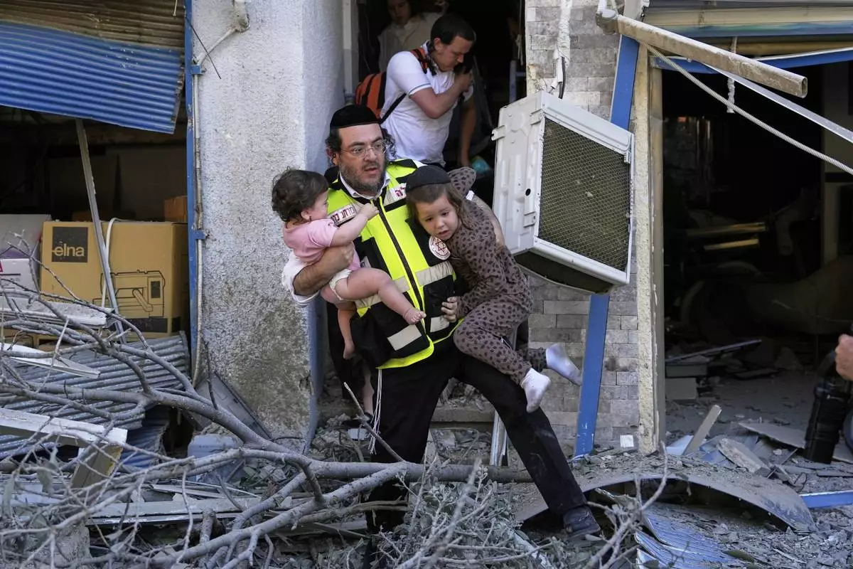 A rescue worker evacuates two children from the site where a missile launched from Iran struck in Haifa, Israel, Sunday, June 22, 2025. (AP Photo/Baz Ratner)