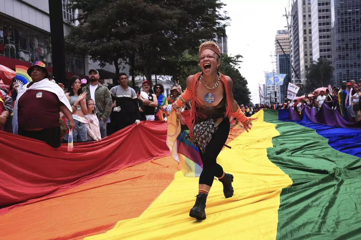 A reveler runs on a large rainbow flag during the annual Pride parade marking LGBTQ+ Pride Month, in Sao Paulo, Sunday, June 22, 2025. (AP Photo/Ettore Chiereguini)