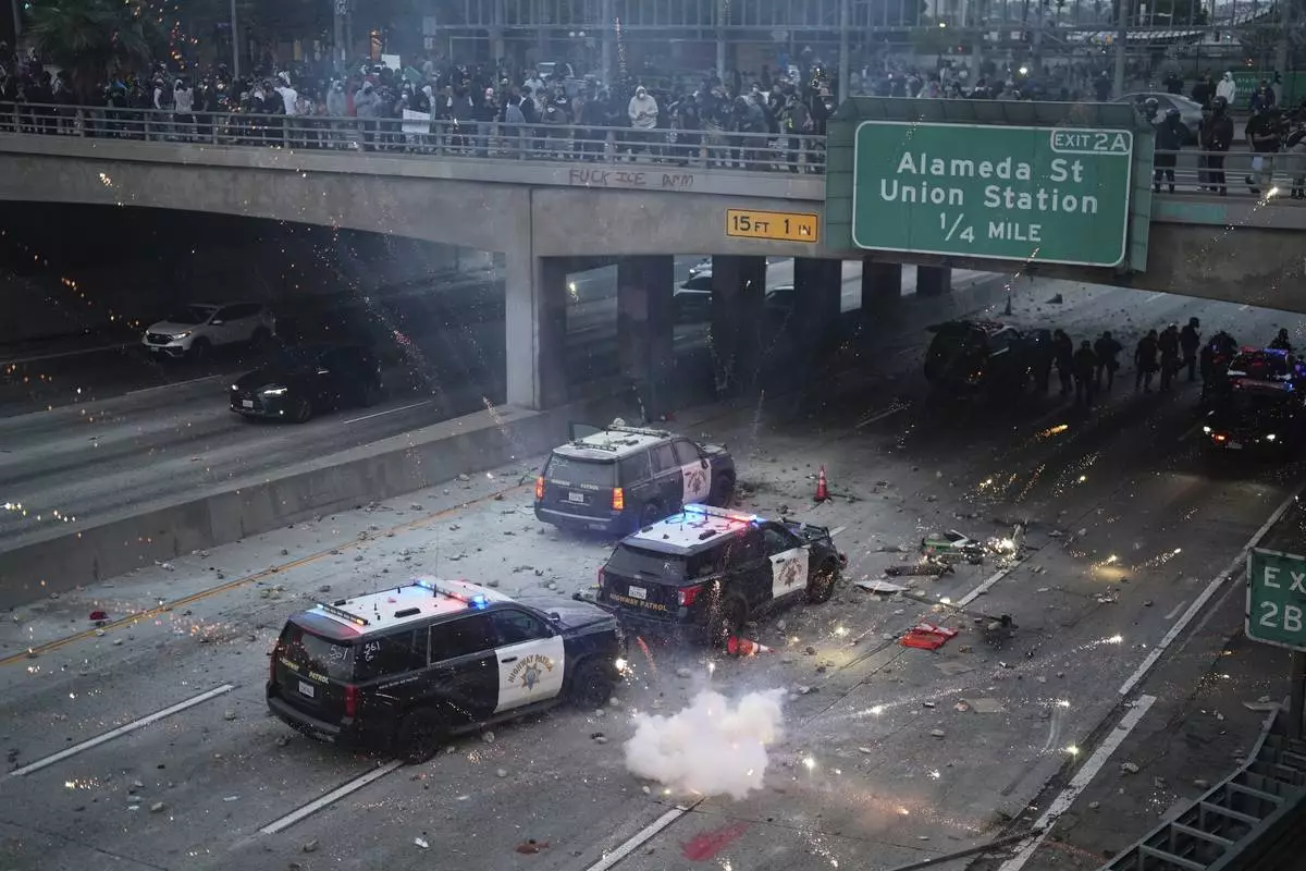 EDS NOTE: OBSCENITY A flash bomb explodes on the 101 Freeway near the metropolitan detention center of downtown Los Angeles, Sunday, June 8, 2025, following last night's immigration raid protest. (AP Photo/Eric Thayer)