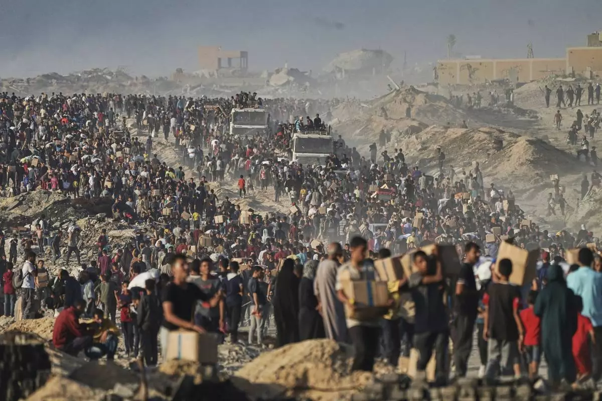 Palestinians carry sacks and boxes of food and humanitarian aid, unloaded from a World Food Program convoy that was heading to Gaza City in the northern Gaza Strip, Monday, June 16, 2025. (AP Photo/Jehad Alshrafi)