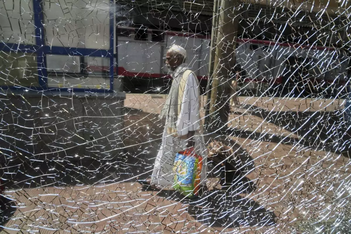 A Sudanese man, who was driven from his home and is now returning, is seen through a broken window as he prepares to enter his train to Aswan at Cairo's Ramses railway station, Egypt, Monday, July 21, 2025. (AP Photo/Amr Nabil)