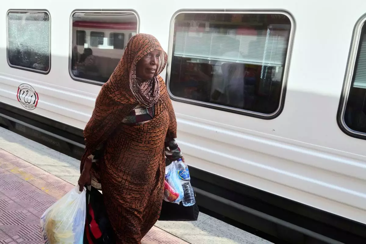 A Sudanese woman, who was driven from her home and is now returning, prepares to enter her train to Aswan at Cairo's Ramses railway station, Egypt, Monday, July 21, 2025. (AP Photo/Amr Nabil)