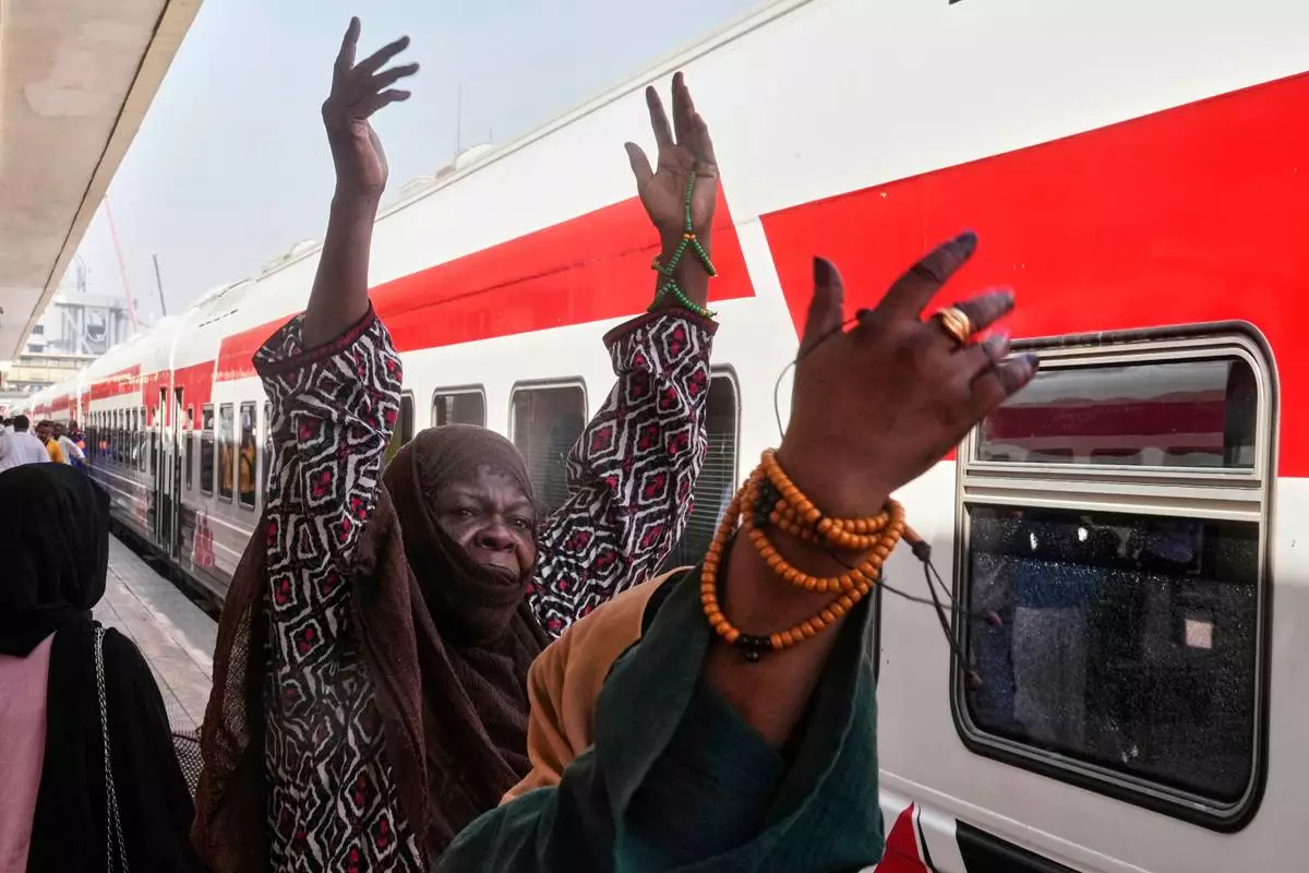 Sudanese people, who were driven from their homes and are now returning, celebrate as they enter their train to Aswan at Cairo's Ramses railway station, Egypt, Monday, July 21, 2025. (AP Photo/Amr Nabil)